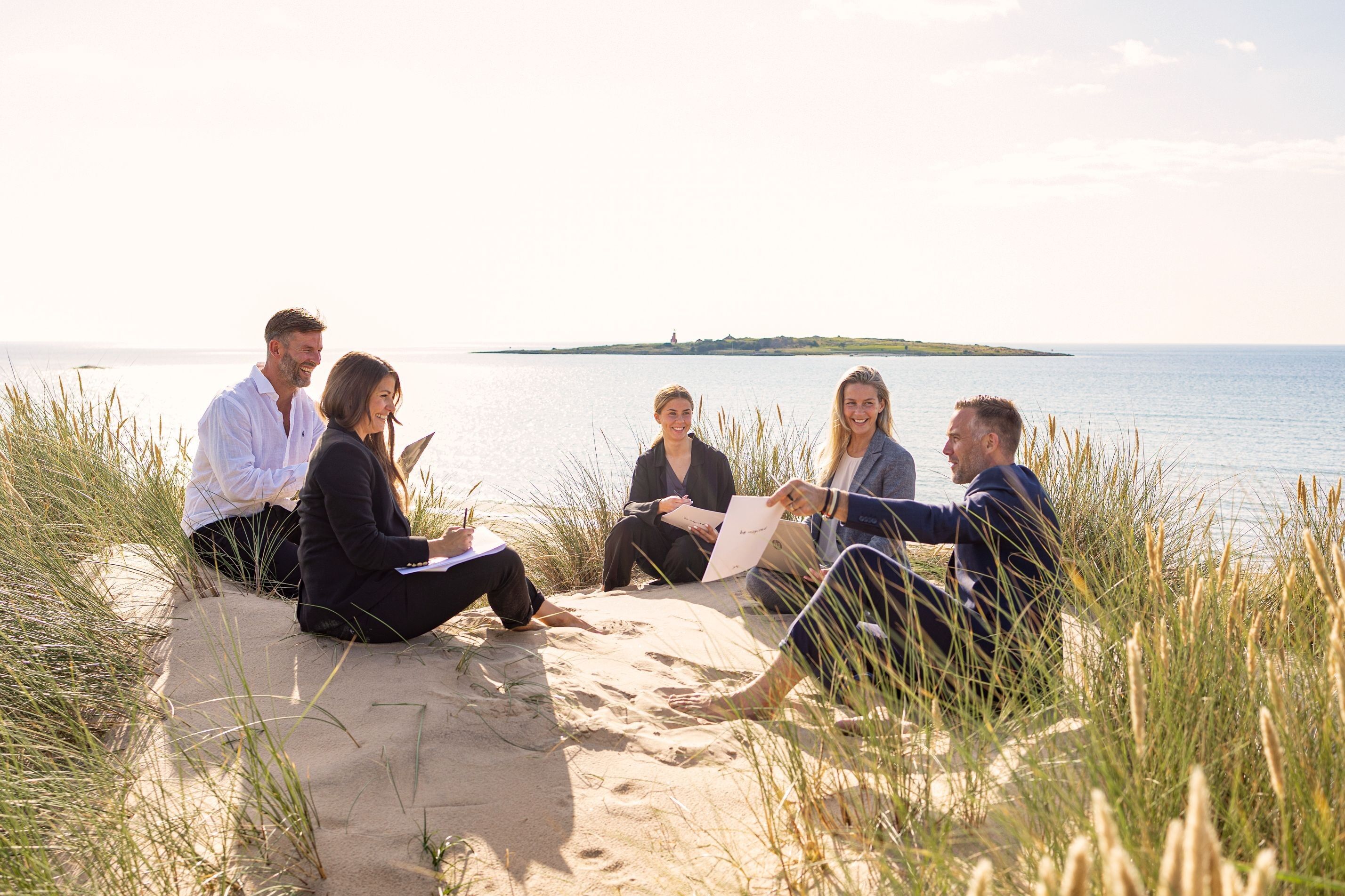 Konferensgrupp sitter i sanddynorna i Tylösand.