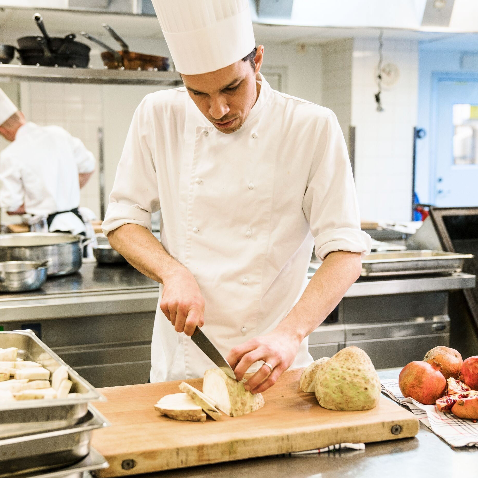 En manlig kock som skär mat i ett restaurang kök på Hotel Tylös