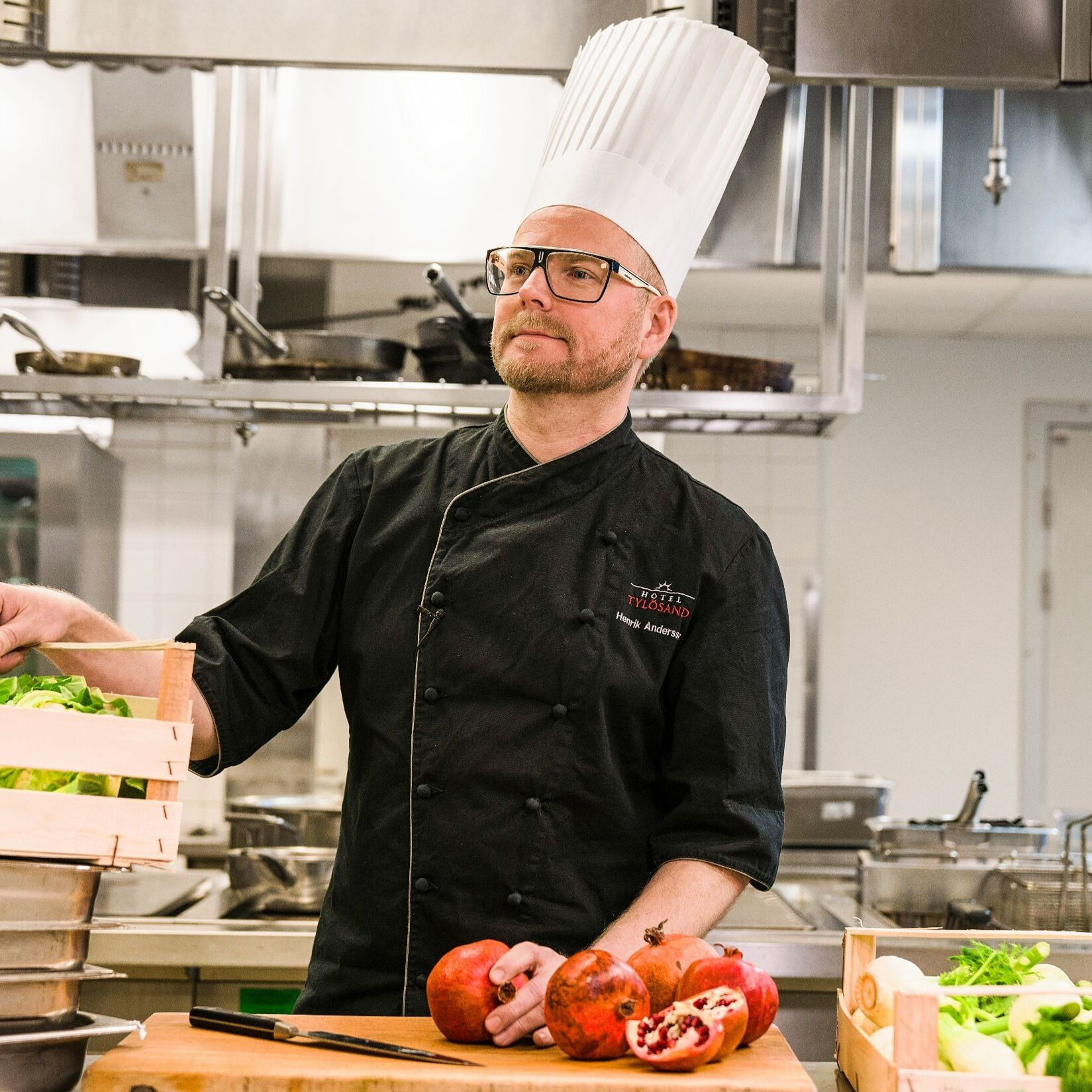 En manlig kock i ett restaurangkök iklädd kockmössa